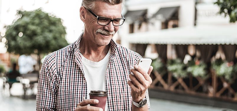 senior man drinking coffee and checking his phone