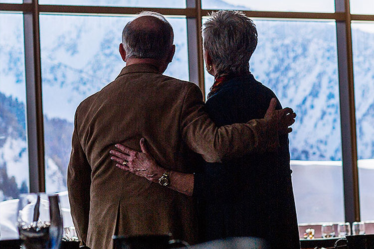 senior couple looking out the window at the snowy mountains